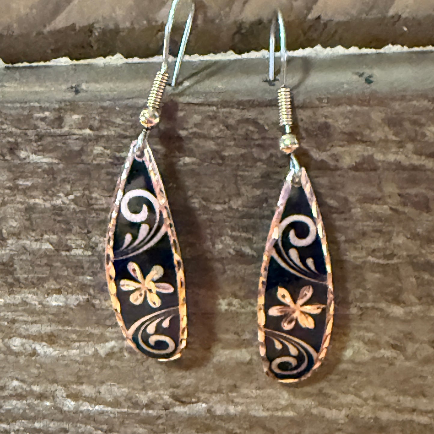 Handcrafted copper rose-gold floral wire drop earrings with black enamel and white swirls.