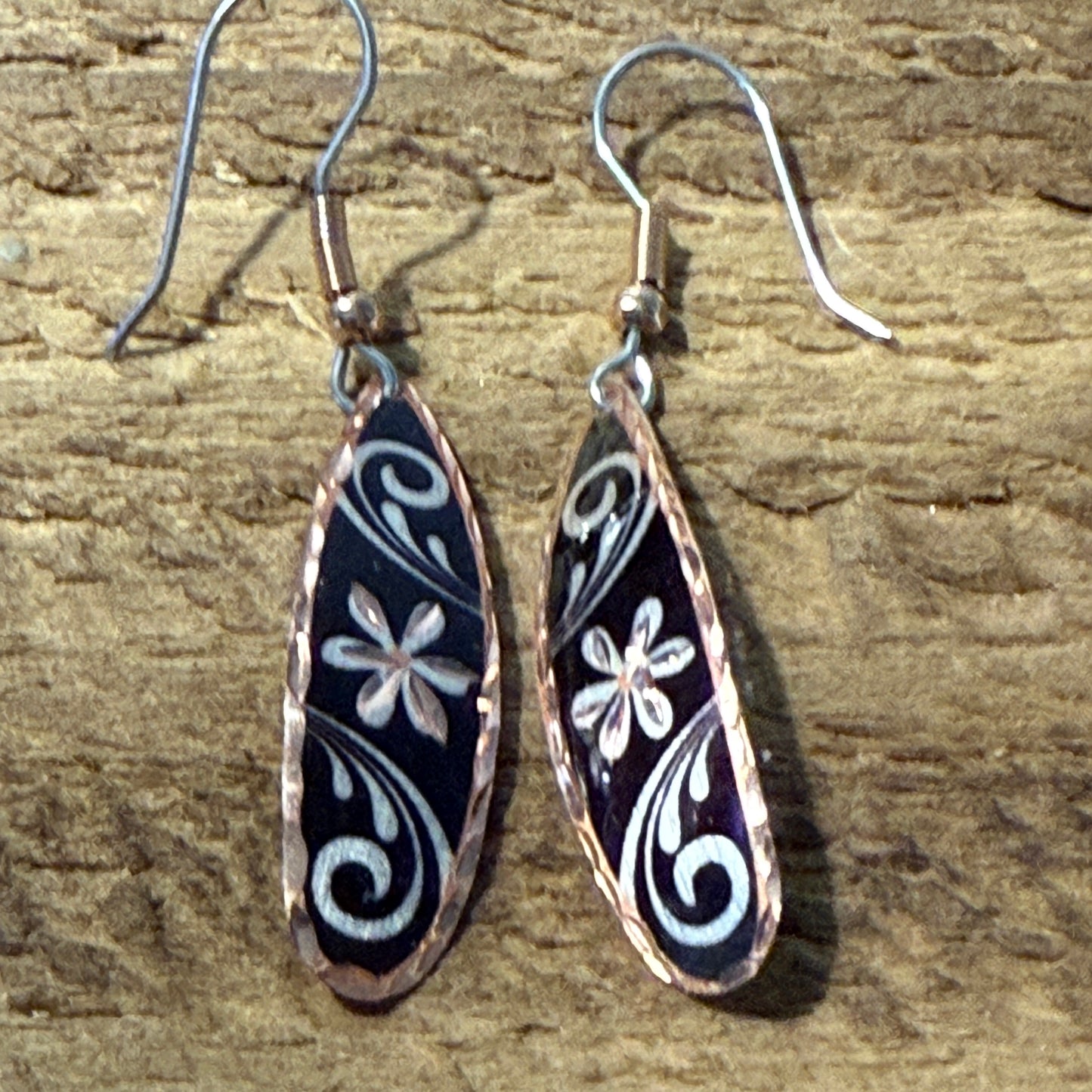 Handcrafted copper rose-gold floral wire drop earrings with black enamel and white floral scrolls.