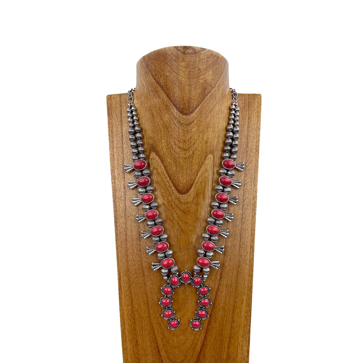 Red stone squash blossom western necklace with faux silver pearl beads and silver detailing on a wooden stand