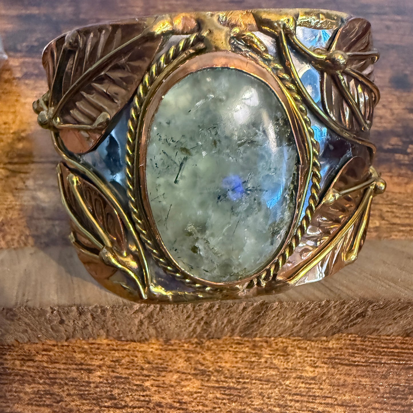 Moss agate centerpiece on a wide cuff bracelet with mixed metals, rope bezel and leaf accents.