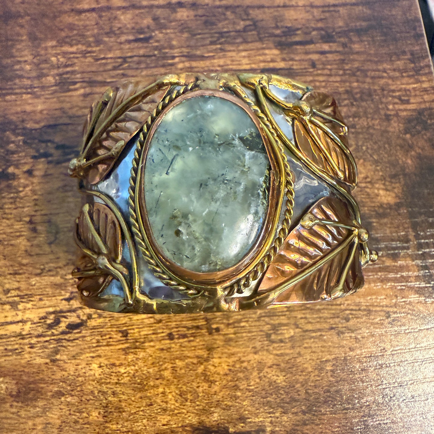 Moss agate centerpiece on a wide mixed-metals cuff bracelet with copper and brass vine accents.