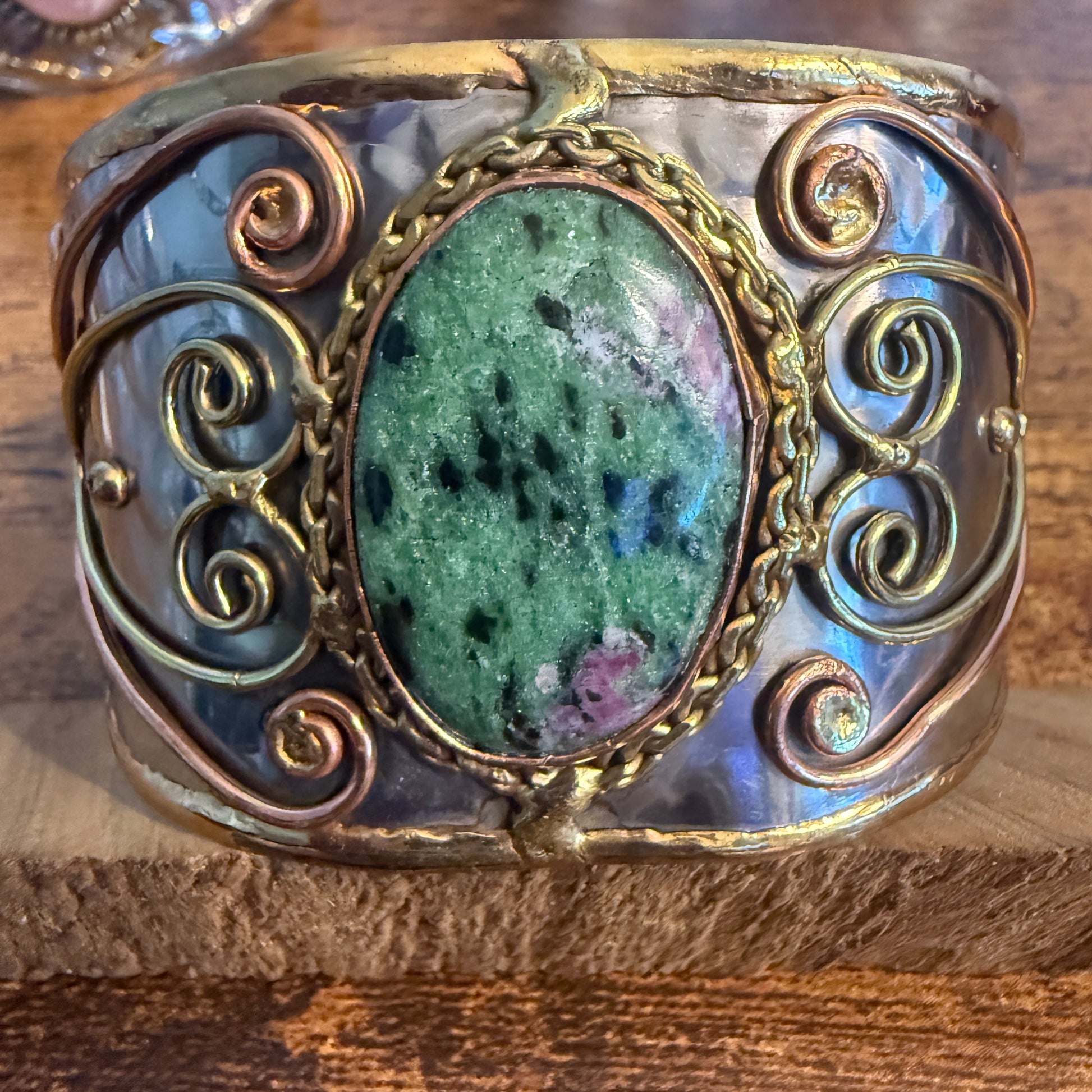 Ruby Zoisite natural stone wide cuff bracelet in mixed metals with gold-toned scrollwork bezel.