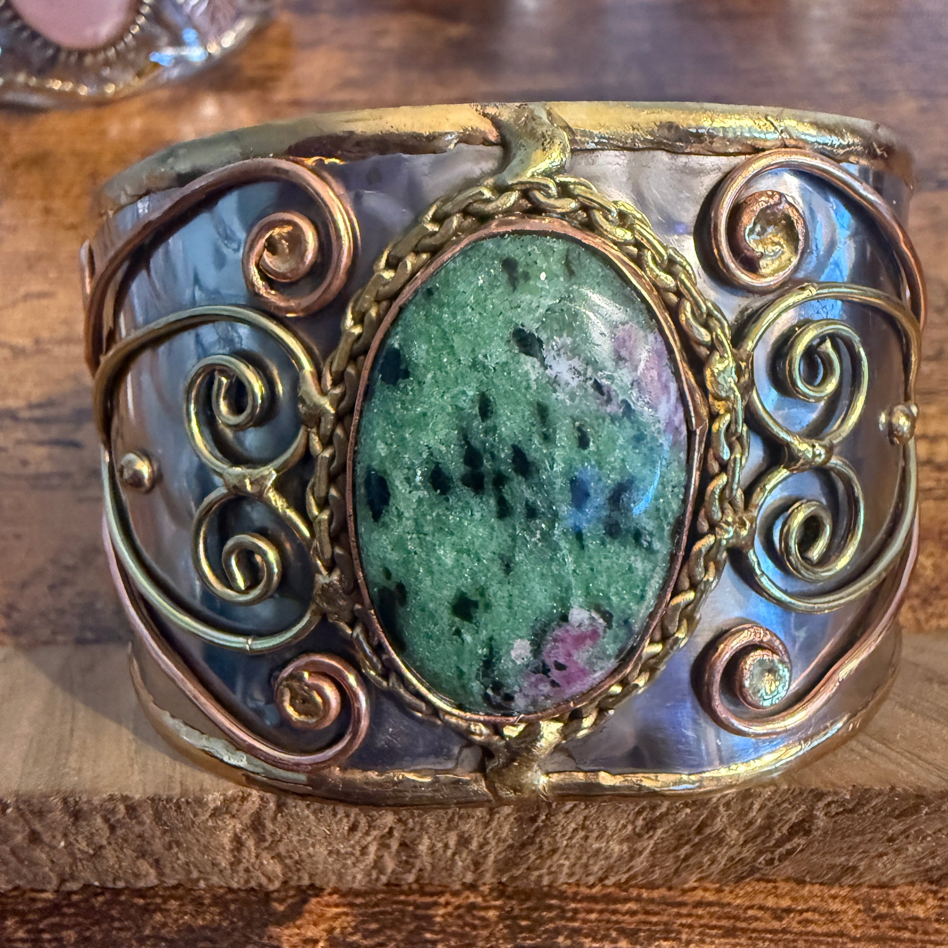 Ruby Zoisite wide cuff bracelet with mixed metals, copper wire scrollwork and a green speckled centerpiece.
