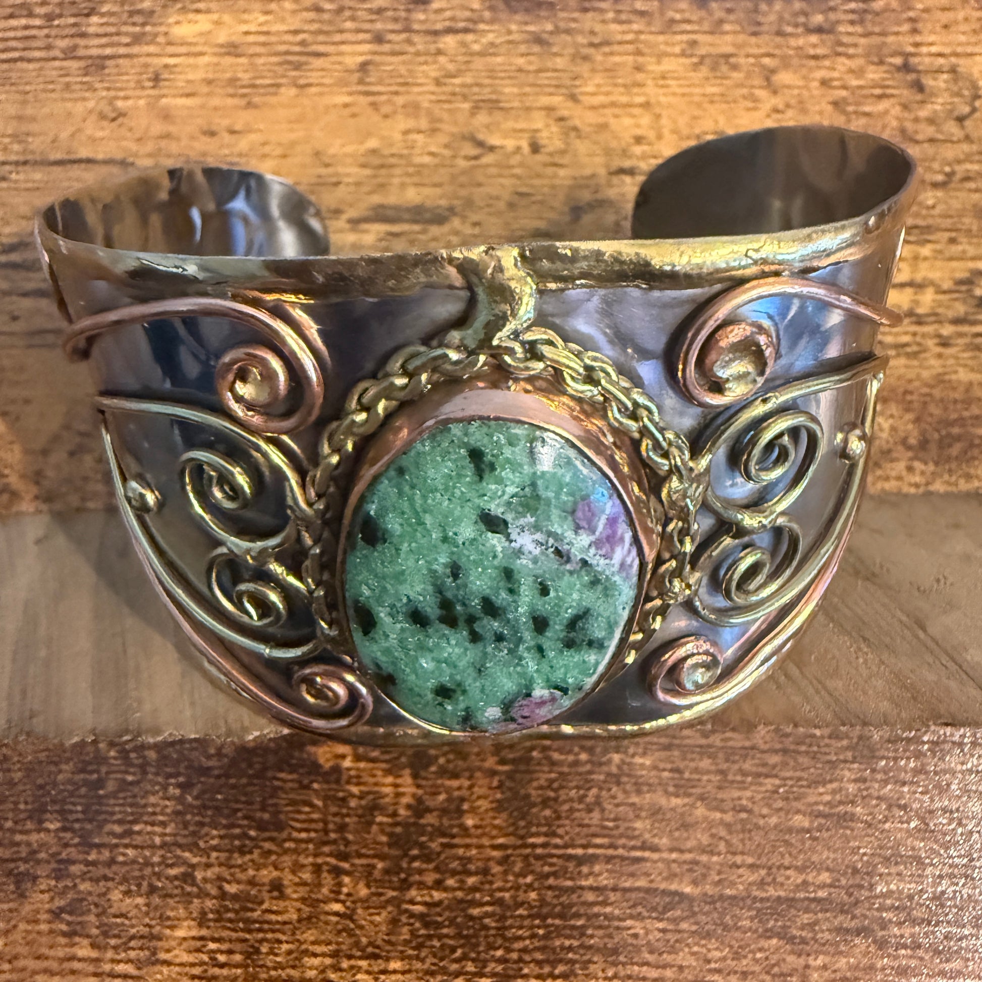 Ruby Zoisite wide cuff bracelet in mixed metals, copper scrollwork, and central green stone.