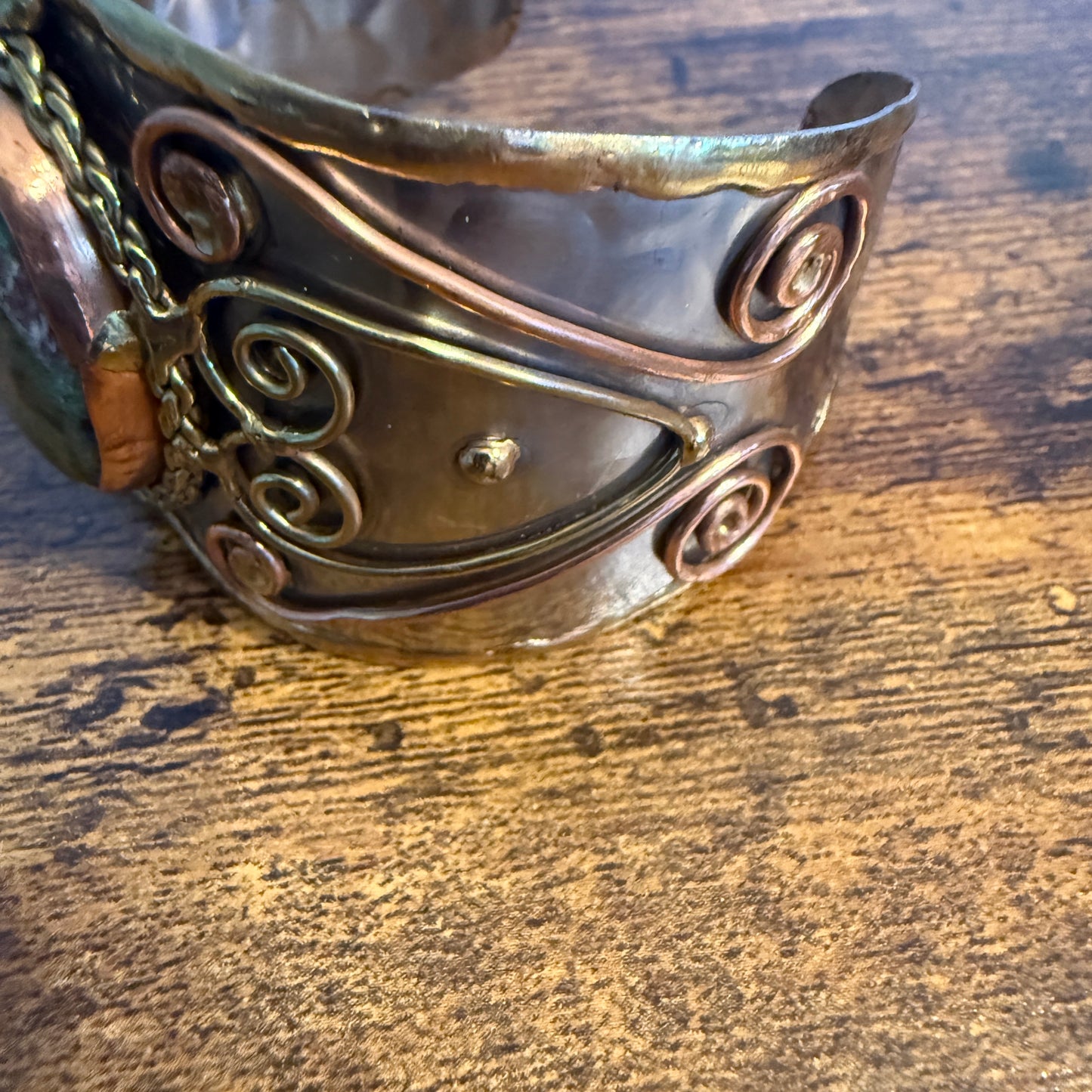 Ruby Zoisite natural stone wide cuff bracelet in mixed metals with copper scrollwork and attached chain.