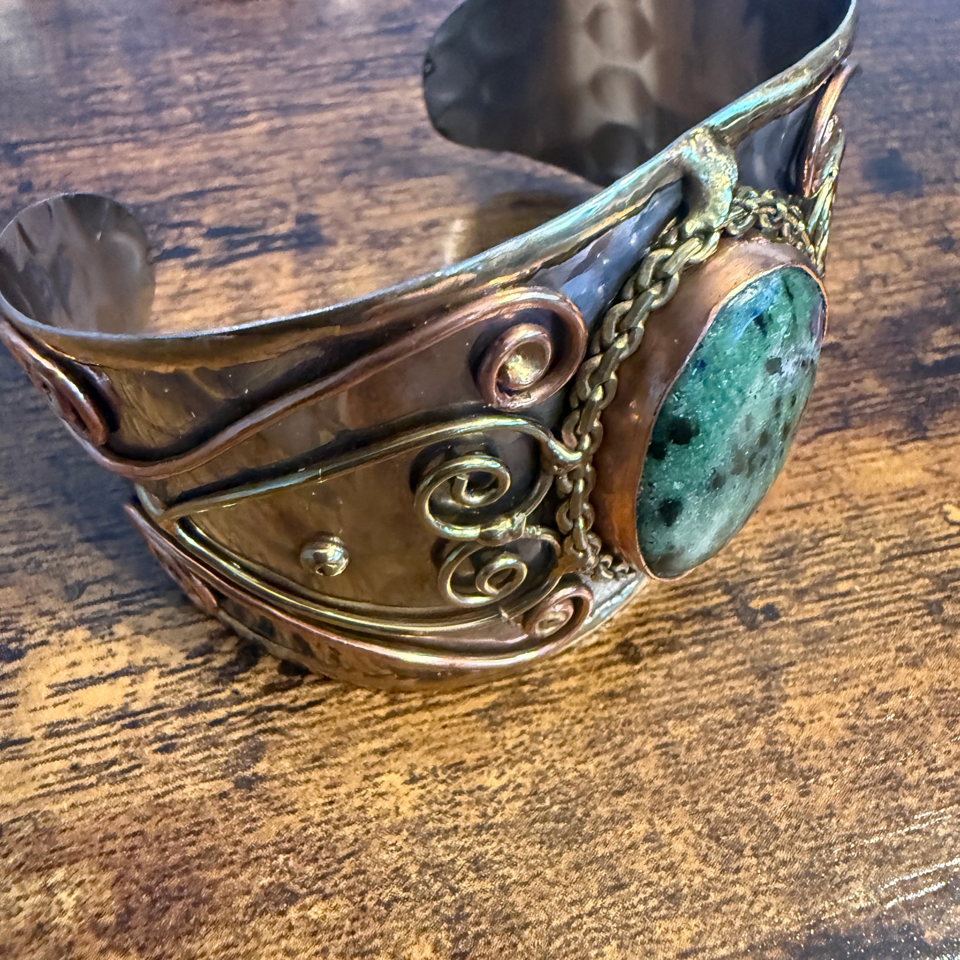 Ruby Zoisite wide cuff bracelet in mixed metals with copper-toned bands, scrollwork, and a green stone centerpiece
